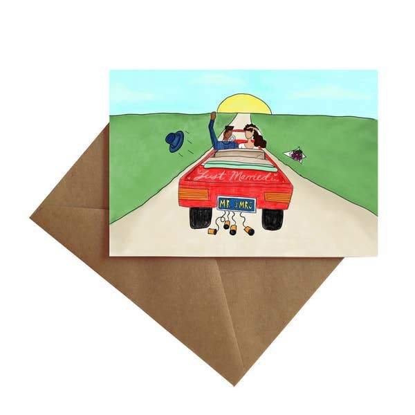 note card featuring an illustration of a newly married couple driving away in a car, shown with brown envelope on white background.