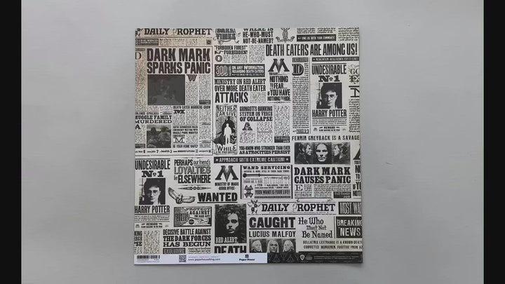Female hands pick up harry potter scrapbook paper featuring black and white newsprint on the front and a pattern of the Deathly Hallows symbol on the back.