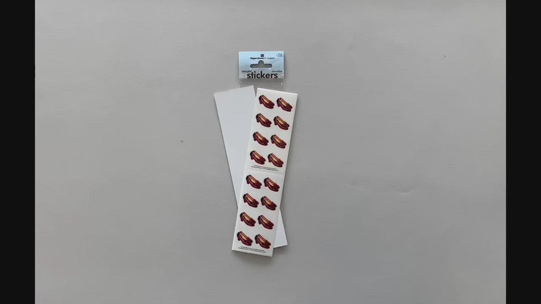 Female hands pick up and show in detail stickers featuring the Wizard of Oz Ruby Slippers.
