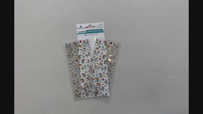 Female hands pick up 1 sheet of mini stickers and shows front and back and then places back on surface on top of package.