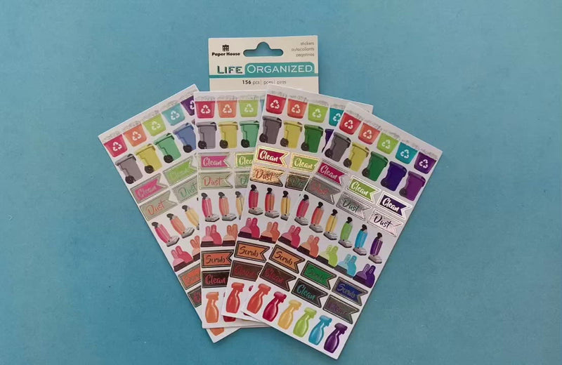 female hands disply 4 sheets of planner stickers featuring colorful cleaning functional stickers on blue background with package.