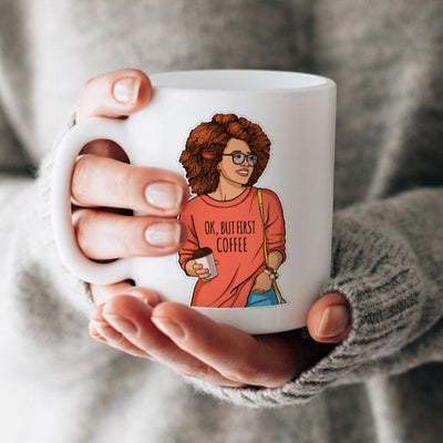 Shaped laptop sticker featuring woman holding a coffee cup and wearing an orange sweatshirt with coffee sentiment, shown in a close up shot on a white mug held in hand.