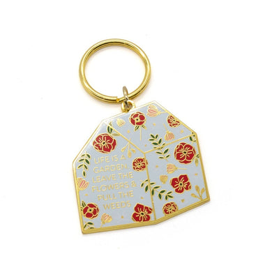 cute keychain featuring a floral and gold greenhouse, shown on white background.