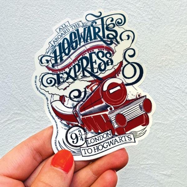 Shaped Harry Potter laptop sticker featuring an illustrated Hogwarts Express graphic in blue and red is shown being held in a hand against a white background.