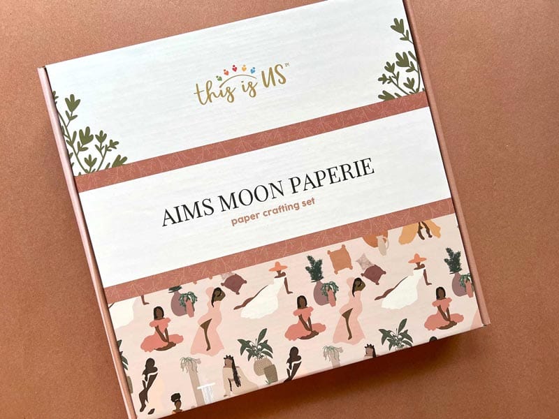 KIT-0129E - Craft Kit - Aim's Moon Paperie - Serenity - Paperie craft kit box with "this is US" gold text, terracotta band, botanical illustrations, and illustrated figures on cream background