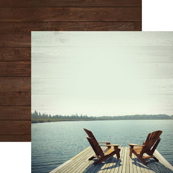 Lake scene scrapbook paper features two chairs on a dock on side one, shown overlappingf a brown wood pattern on side two.