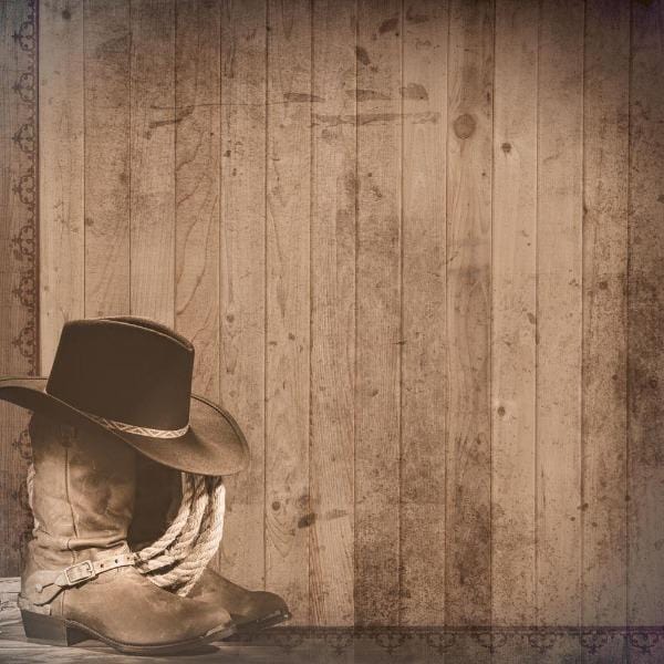 scrapbook paper featuring photo-real brown cowboy boots and hat shown against a brown wood pattern.
