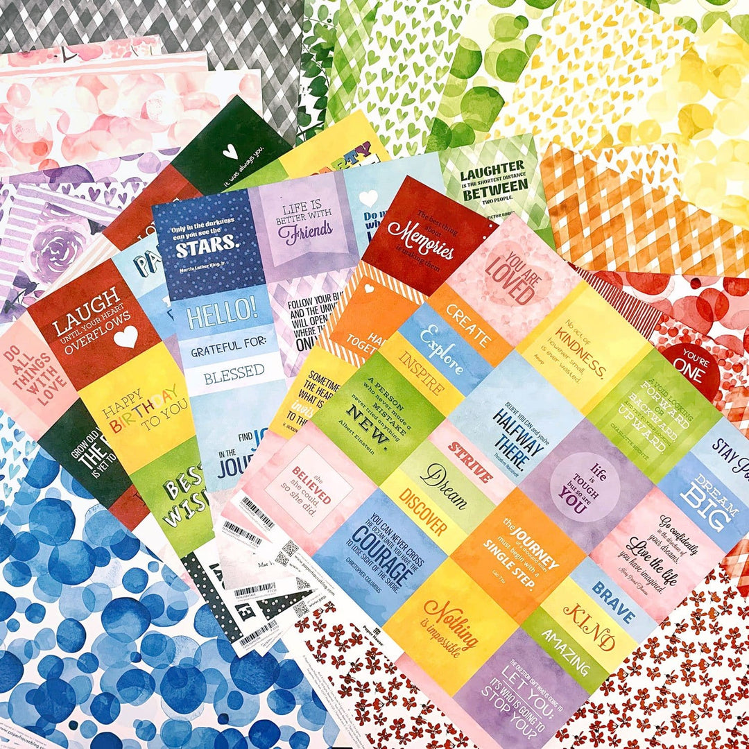 PSET-0001E - Scrapbook Paper - Colorways 30 Sheet Bundle - Colorful scrapbook paper sheets with inspirational text and patterned designs in rainbow colors displayed flat lay