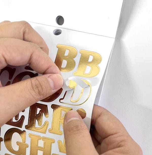 STBK-1000E - Alphabet Stickers - Alphabooks Classic Serifs - Hand peeling gold foil alphabet stickers with serif lettering from a white sheet