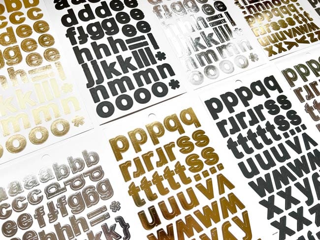 STBK-1002E - Alphabet Stickers - Alphabooks Classic Block - Multiple sheets of adhesive letter stickers in black, gold, and silver metallic finishes arranged on a white background
