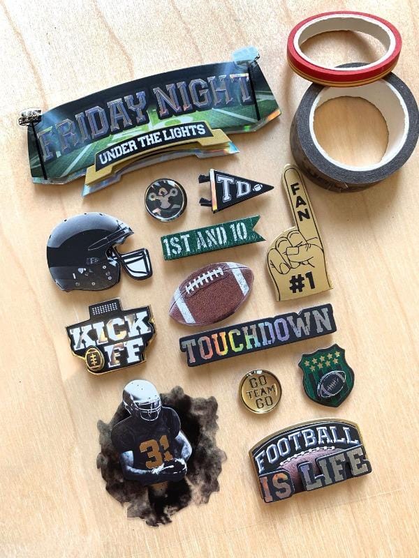 3D scrapbook stickers featuring football imagery with gold details shown next to 2 rolls of washi tape on a wood surface.