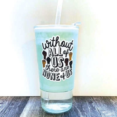 Shaped laptop sticker featuring "Without All of Us" in black text with multi colored illustrated power fists on a white background,  shown on a drinking glass filled with blue liquid and a straw.