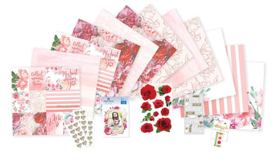 craft kit featuring scrapbook papers, stickers and washi tape with pink florals and patterns, shown on white background.